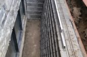 a building under construction with a retaining wall around a basement window